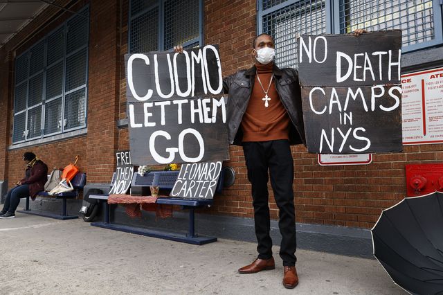 Pastor Isaac Scott holds up signs 'Cuomo Le Them Go' and 'No Death Camps in NYS' during a vigil organized by justice reform advocates and local faith leaders in response to the recent death of New York State inmate Leonard Carter in front of the Queensboro Correctional Facility.